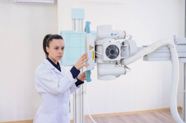  Röntgen makinesini ayarlayan bir kadın radyologun yan görüntüsü.