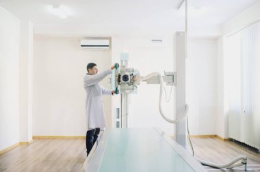  Röntgen cihazını ayarlayan bir erkek radyologun yan görüntüsü.