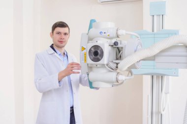 Röntgen makinesini muayene odasında ayarlayan bir erkek radyologun ön görüntüsü.