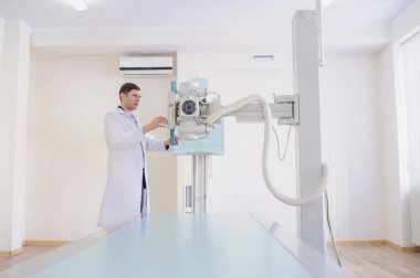  Röntgen cihazını ayarlayan bir erkek radyologun yan görüntüsü.