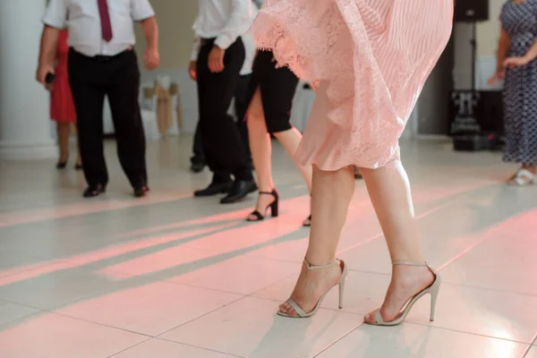 婚宴上穿着时髦的高跟鞋在地板上跳舞的女性腿的近照 — 图库照片
