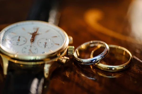 close up photo of groom hand watch and wedding rings