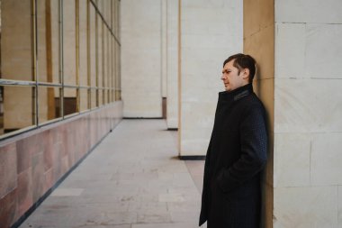 Klasik palto giymiş genç bir adamın yan görüntüsü.