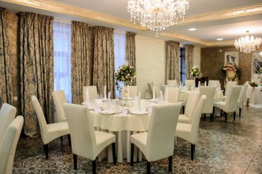 Düğün masası, perdeleri beyaz renkli bir ziyafet salonunda.