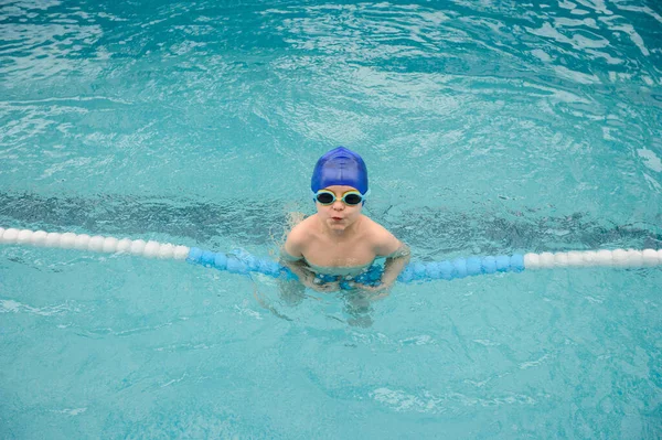 7歳の男の子がプールで遊んだり泳いだり — ストック写真