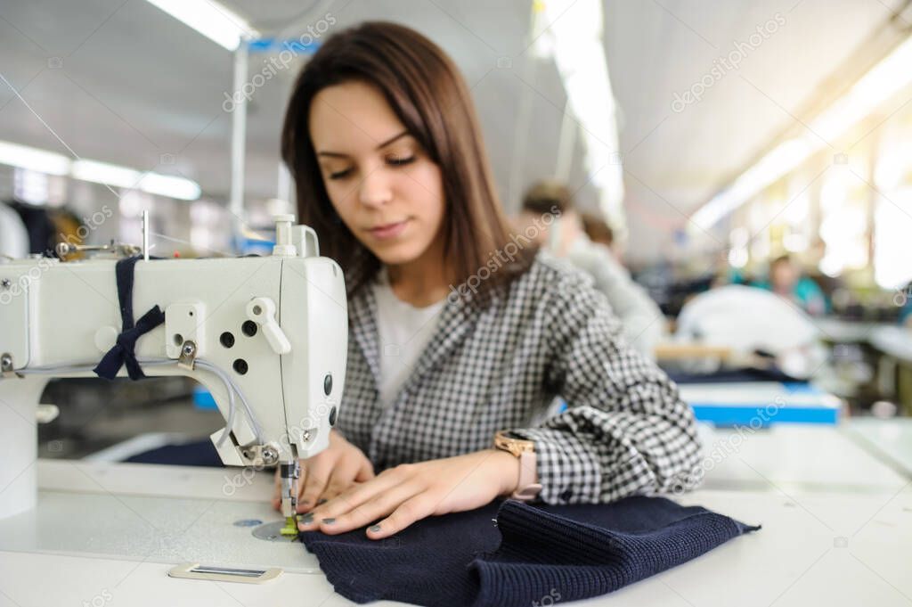 close up photo of a young woman sewing with sewing machine in a factory