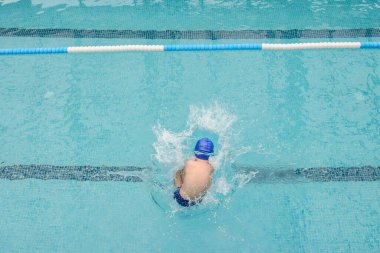 Yüzme havuzunda oynayan ve yüzen 7 yaşındaki bir çocuğun en iyi görüntüsü.
