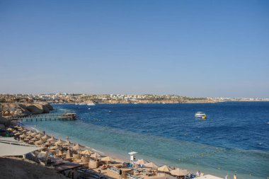 Yaz tatili için cennet gibi bir tropik tatil beldesindeki kumsalda Thatched plaj şemsiyeleri ve şezlongları