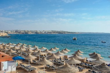 Yaz tatili için cennet gibi bir tropik tatil beldesindeki kumsalda Thatched plaj şemsiyeleri ve şezlongları