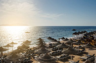 Yaz tatili için cennet gibi bir tropik tatil beldesindeki kumsalda Thatched plaj şemsiyeleri ve şezlongları