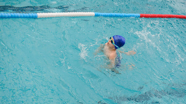 top view of a 7-year boy playing and swimming in the swimming pool