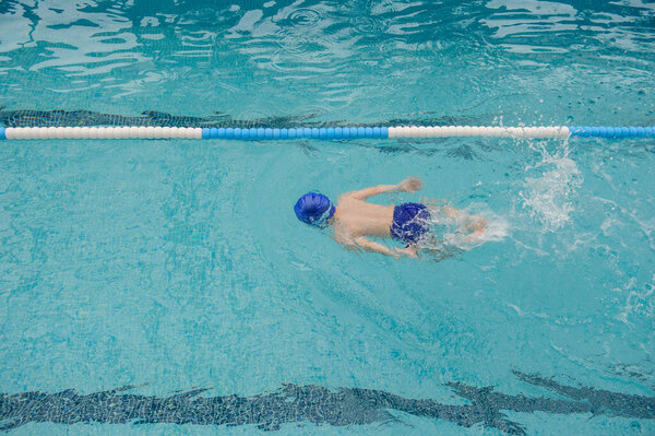 top view of a 7-year boy playing and swimming in the swimming pool