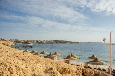 Yaz tatili için cennet gibi bir tropik tatil beldesindeki kumsalda Thatched plaj şemsiyeleri ve şezlongları
