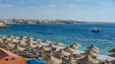 Yaz tatili için cennet gibi bir tropik tatil beldesindeki kumsalda Thatched plaj şemsiyeleri ve şezlongları