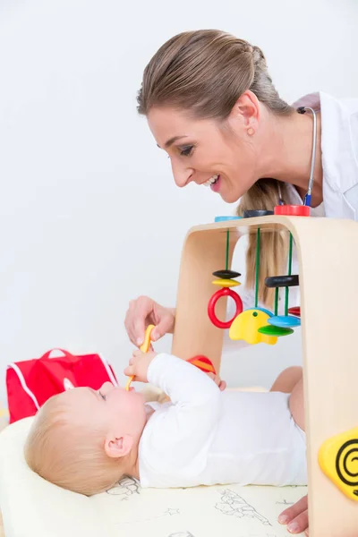 Pediatra dedicado brincando com um bebê saudável e ativo — Fotografia de Stock