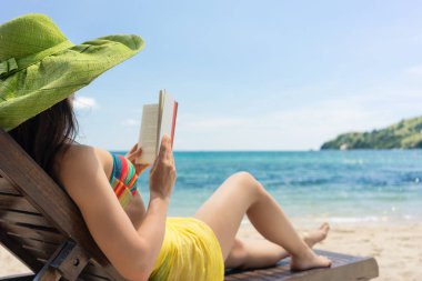 Genç güzel kadın güneşli bir günde sahilde bir kitap okuma