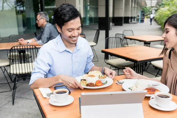 Pria dan wanita muda Asia tersenyum sambil makan siang bersama — Stok Foto