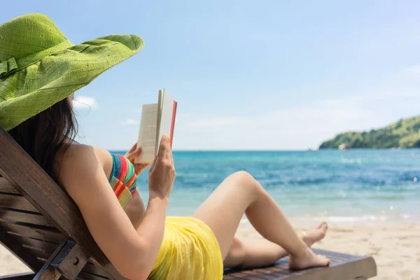 Wanita cantik muda membaca buku di pantai di hari yang cerah — Stok Foto