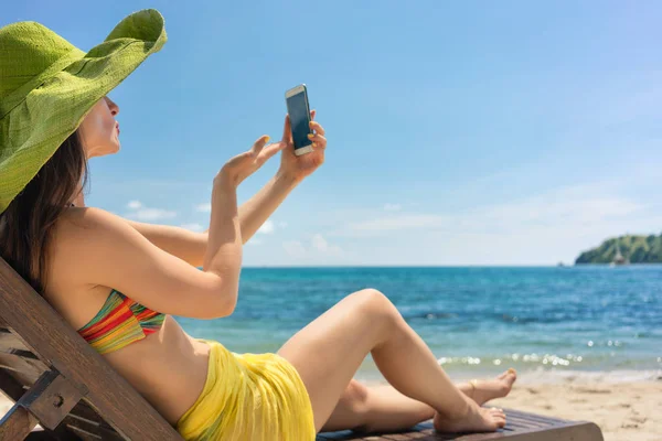 Молодая женщина отправляет любовное послание через селфи фото на пляже — стоковое фото