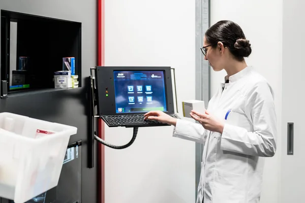 Farmaceut med en dator samtidigt hantera drogen beståndet — Stockfoto