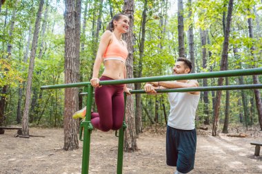 Sağlıklı kadın üzerinde paralel bar erkek arkadaşıyla egzersiz