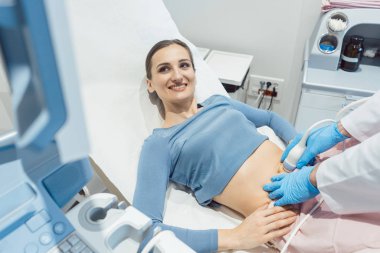 Kadın ve Doktor muayene sırasında ultrasonik ekrana bakarak