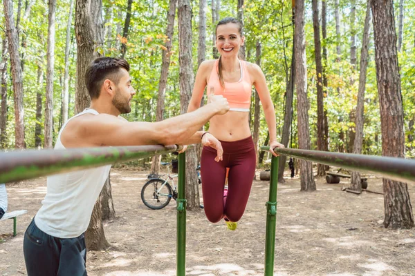 Fit vrouw uitoefenen op de parallelle bar met haar vriendje — Stockfoto