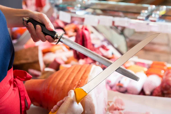 Carnicera afilando sus cuchillos — Foto de Stock