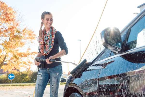 Mulher limpando seu veículo em auto-serviço de lavagem de carro — Fotografia de Stock