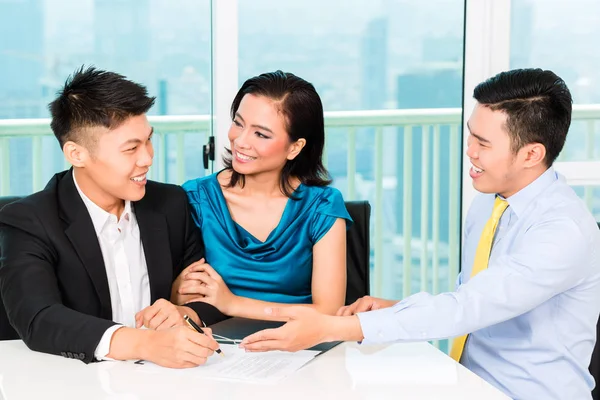 Asian banker selling insurance to couple — Stock Photo, Image