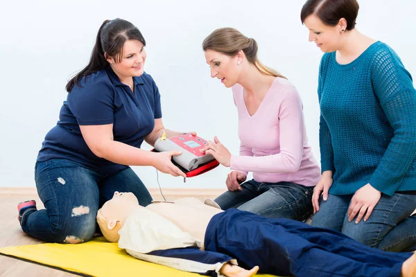 Estagiários de primeiros socorros aprendendo a usar desfibrilador para reanimação — Fotografia de Stock