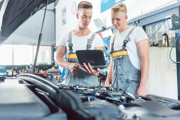 Mecânico de auto experiente usando um laptop para códigos de erro do motor de varredura — Fotografia de Stock