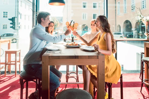 Молодые друзья пьют коктейли перед едой морепродуктов в ресторане — стоковое фото