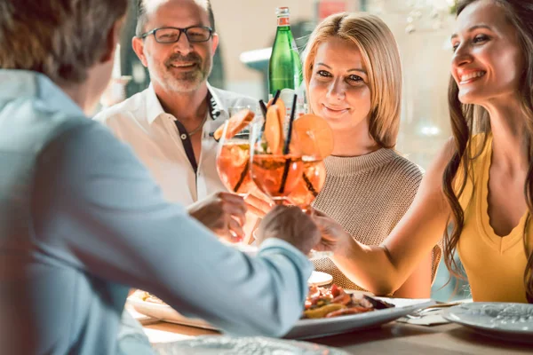 Jonge vrienden roosteren met cocktails voor schaal-en schelpdieren eten in een restaurant — Stockfoto