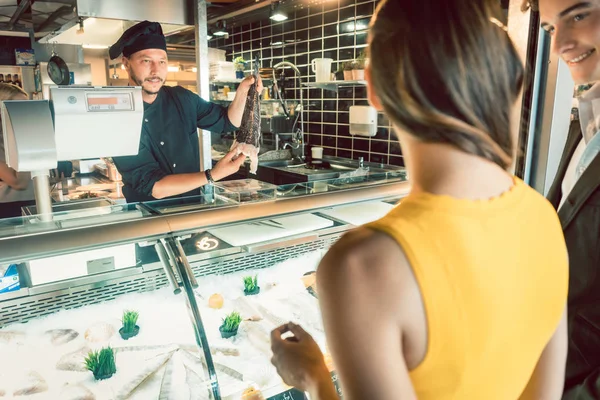 Erfahrener Koch holt frischen Fisch aus dem Gefrierfach, um ihn zu kochen — Stockfoto