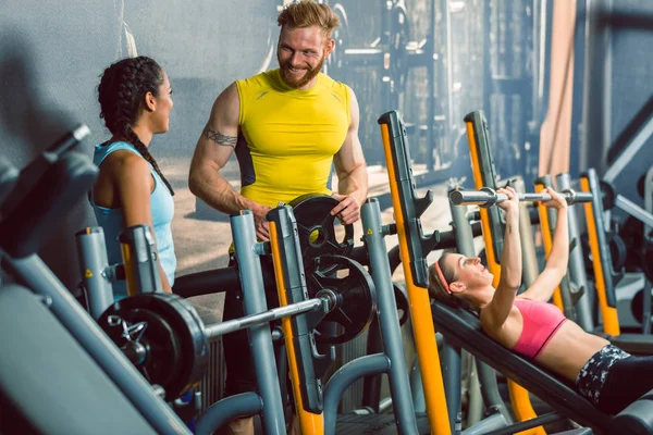 Guapo culturista hablando con una hermosa mujer en forma en el gimnasio — Foto de Stock