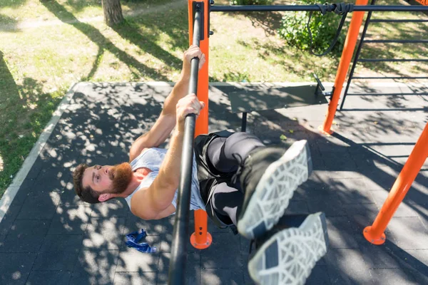 Hombre fuerte haciendo colgar la pierna plantea para los músculos abdominales durante el entrenamiento — Foto de Stock