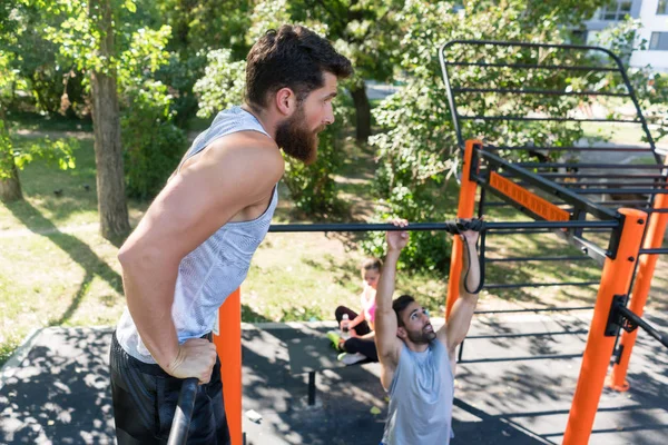 Twee gespierde jonge mannen doen lichaamsgewicht oefeningen in een moderne outdoor fitness — Stockfoto