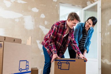 Genç çift yeni ev yenileme sırasında kutuları açma