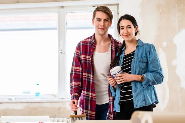 Retrato de una feliz pareja joven sosteniendo herramientas para la remodelación del hogar — Foto de Stock