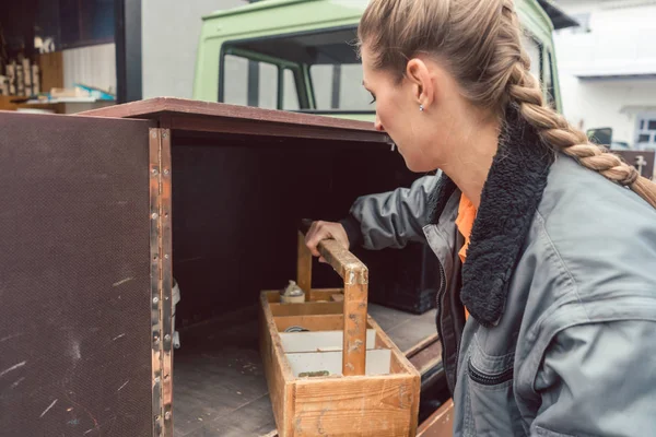 Woman carpenter loading tools in mobile workshop transporter