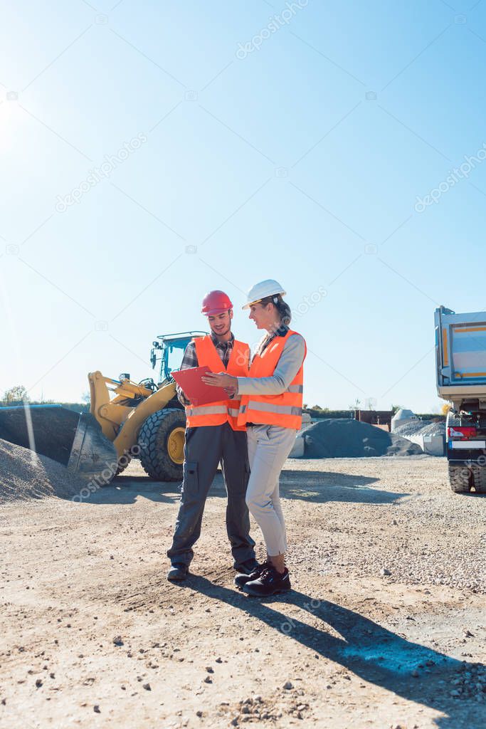 Worker and engineer on earthworks construction site planning 