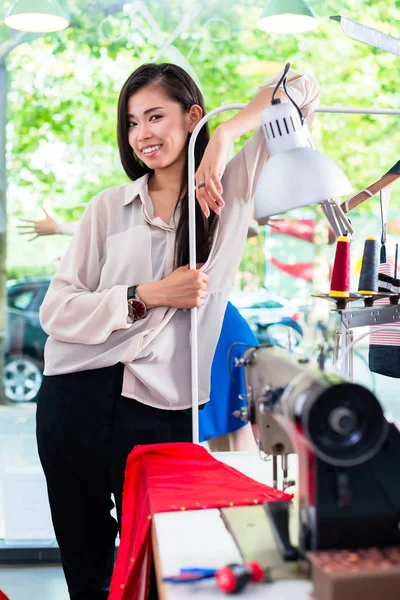 Asian tainlor or fashion designer leans on sewing desk — Stock Photo, Image