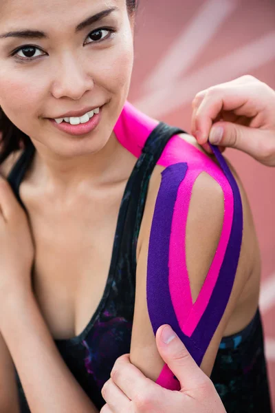 Woman taping with therapeutic tape on cinder track of stadium — Stock Photo, Image