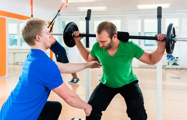 Athlete weightlifting in gym studio with his training partner — Stock Photo, Image