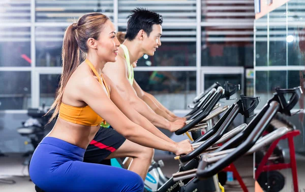 Deportiva pareja asiática haciendo indoor cycling en gimnasio —  Fotos de Stock