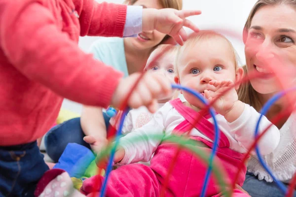 Grupp av glada unga mödrar titta på sina söta och friska barn spela — Stockfoto