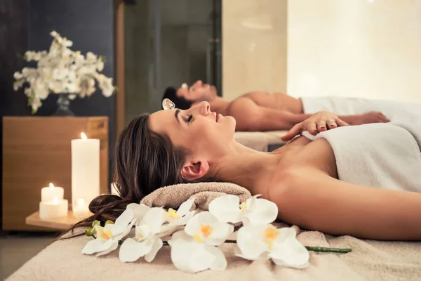 Man relaxing with his partner on massage beds at wellness center — Stock Photo, Image