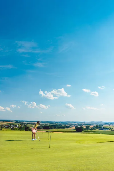 Určuje mladá žena cvičit golf na trávě výcvikovém prostoru — Stock fotografie