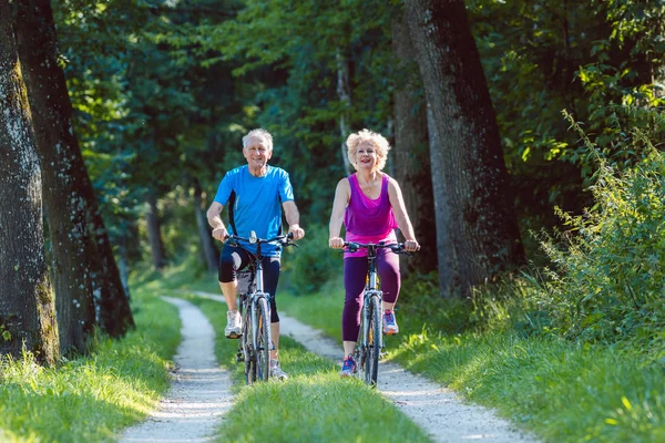 Pareja mayor feliz y activa montando bicicletas al aire libre en el parque — Foto de Stock